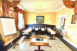 A conference room with a long table, chairs, a whiteboard, and a chandelier.
