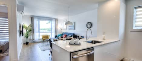 A modern kitchen with a central island, stainless steel appliances, and a dining area with a sofa and chairs.