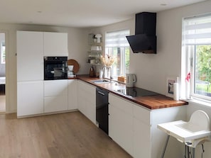 A modern kitchen with white cabinetry, a built-in oven, and a black range hood. - 6 Person Holiday Home in Melby (Melby)