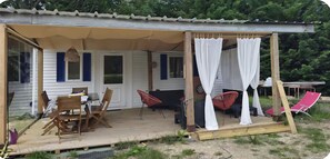 Un área de estar al aire libre techada con mesa, sillas y un toldo.