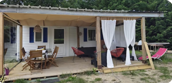 Un área de estar al aire libre techada con mesa, sillas y un toldo.