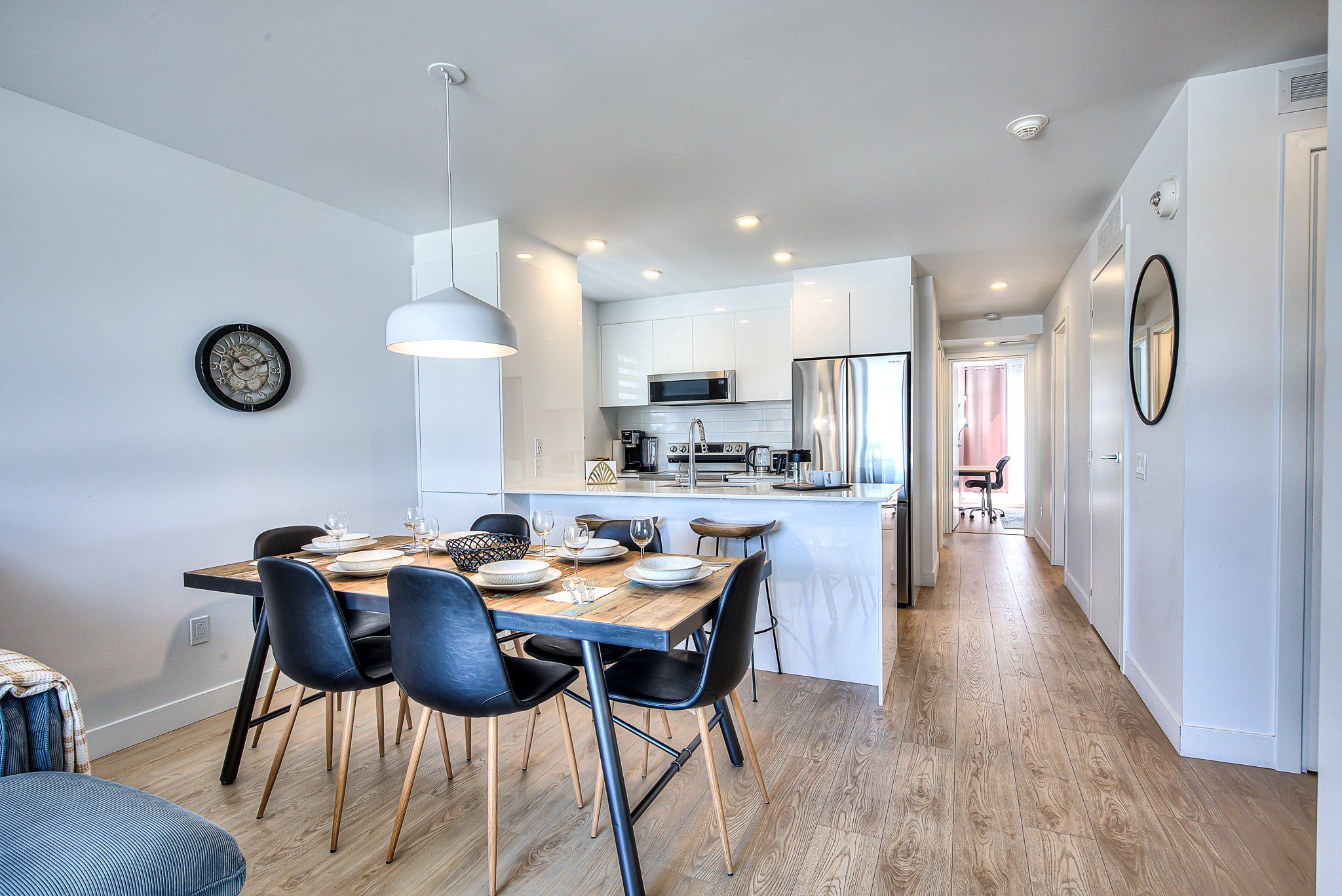 A modern kitchen with white cabinets, a stainless steel refrigerator, and a microwave.
