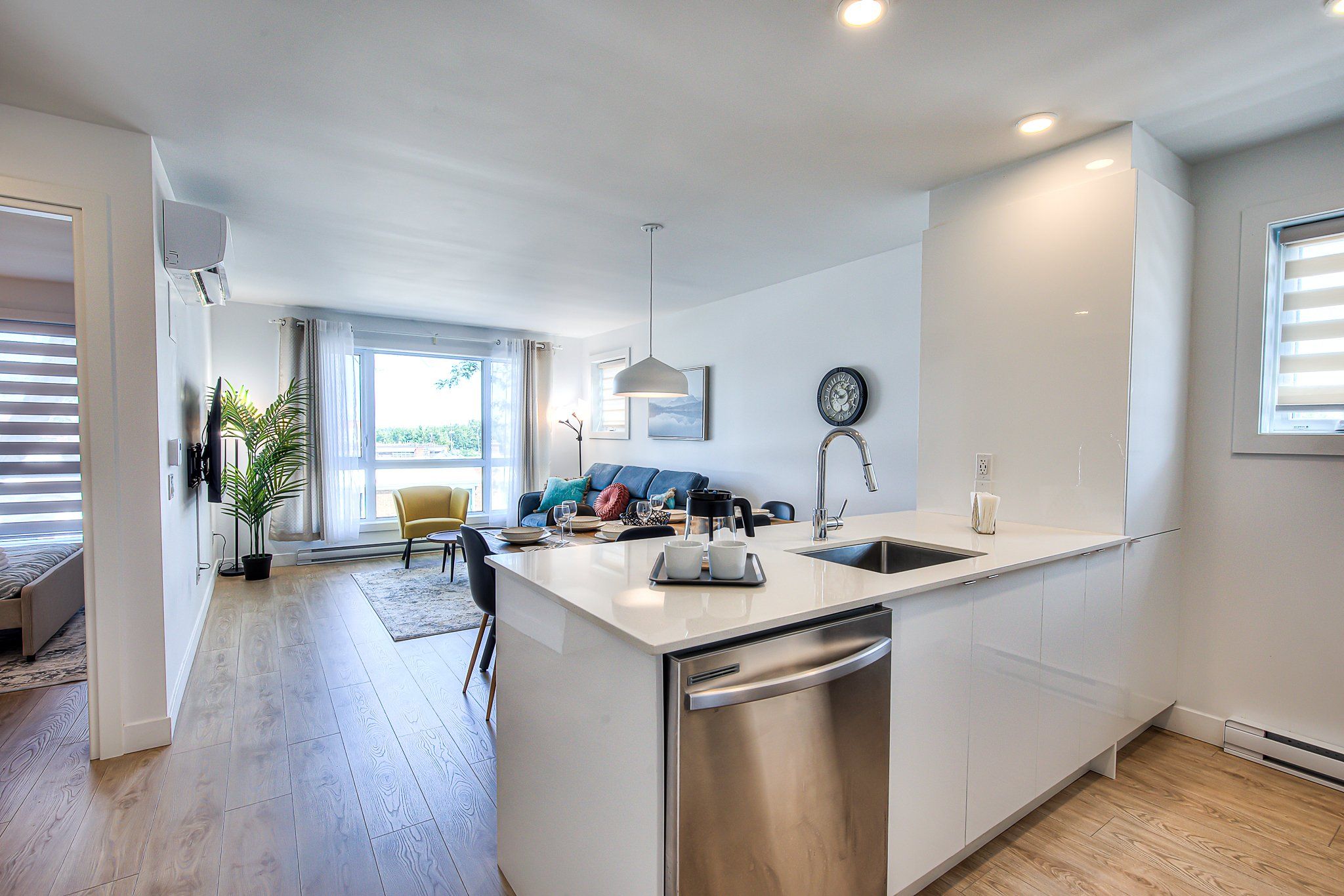 A modern kitchen with a central island, stainless steel appliances, and a dining area with a sofa and chairs.