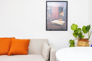 A living room with a sofa, a framed picture on the wall, and a potted plant. - Modern 2-Bed Flat in Highbury • Victoria Line (London)