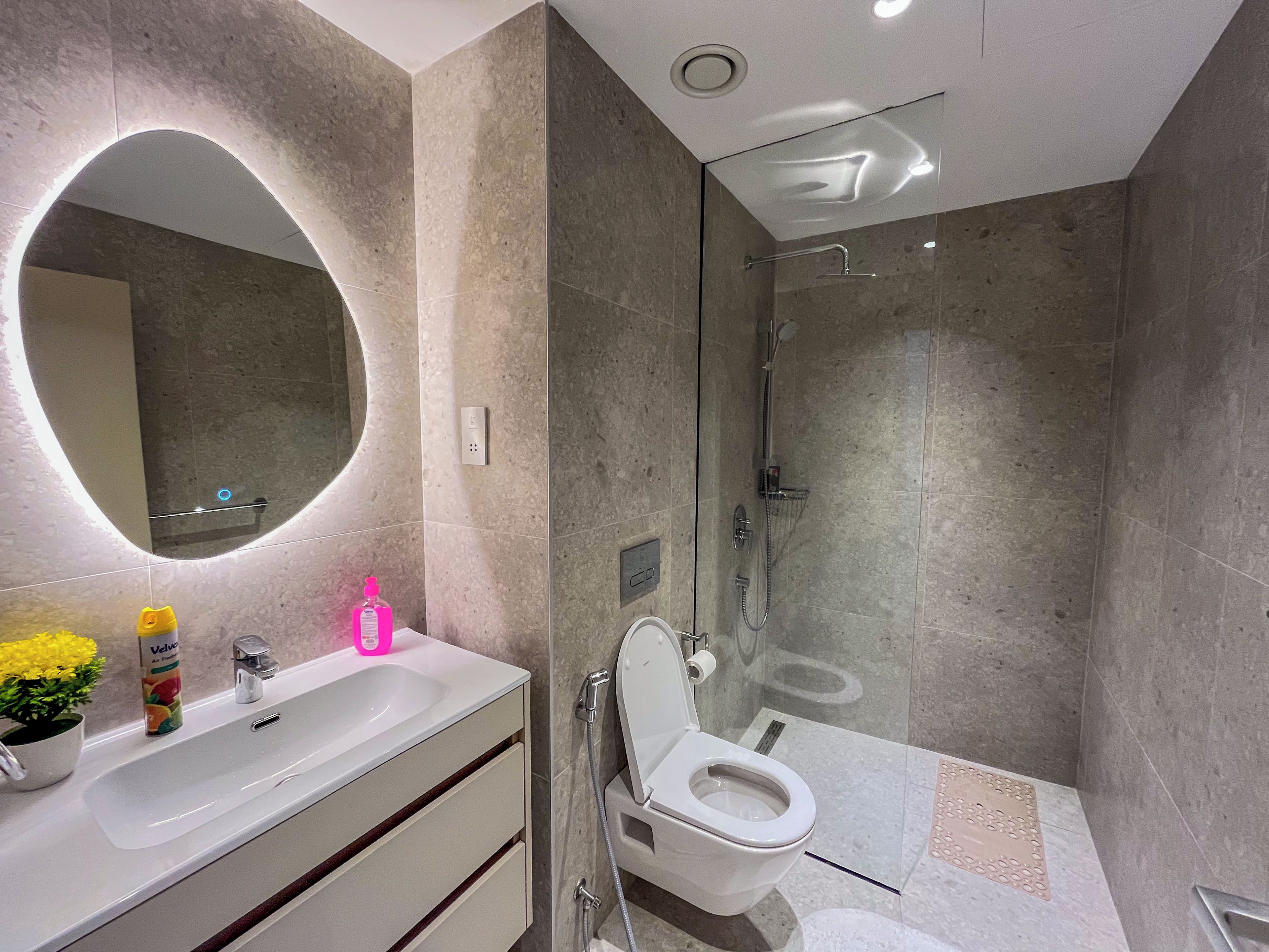 A modern bathroom with a glass-enclosed shower, a white sink with a mirror, and a toilet.