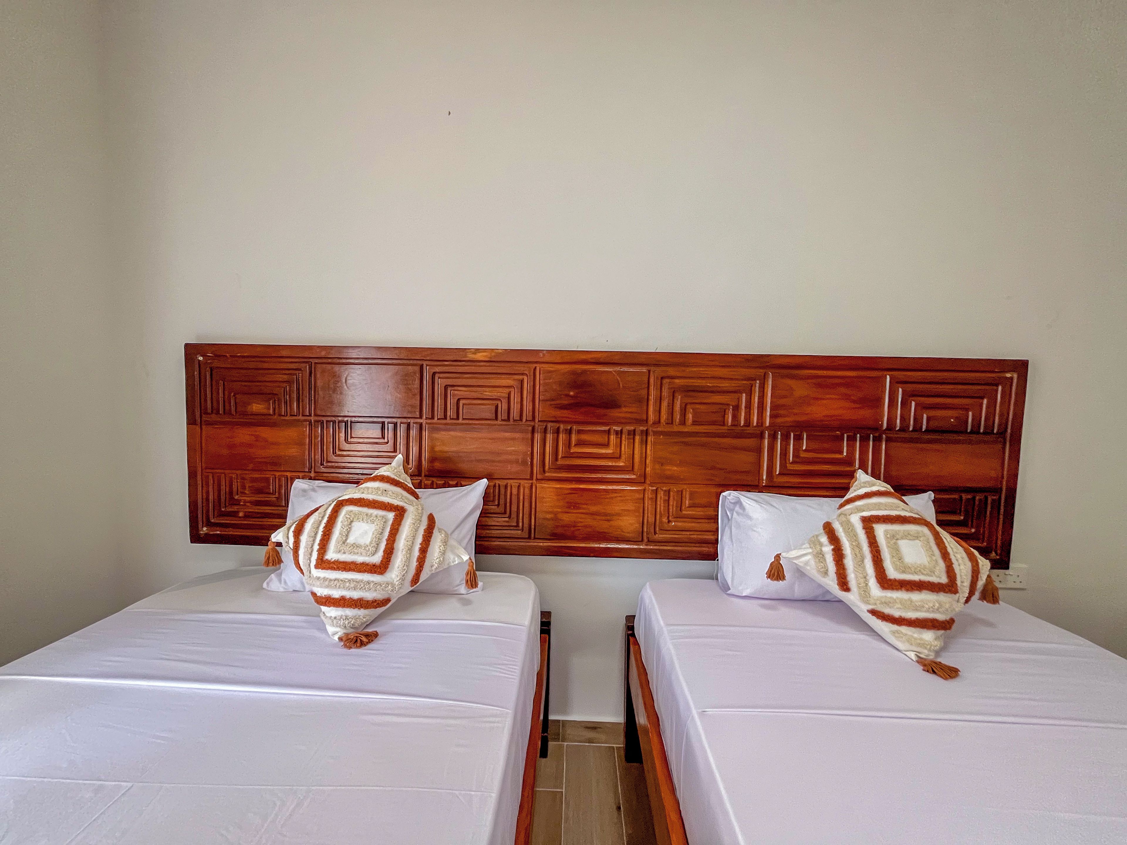 Dos camas individuales con cabeceros de madera y ropa de cama blanca.