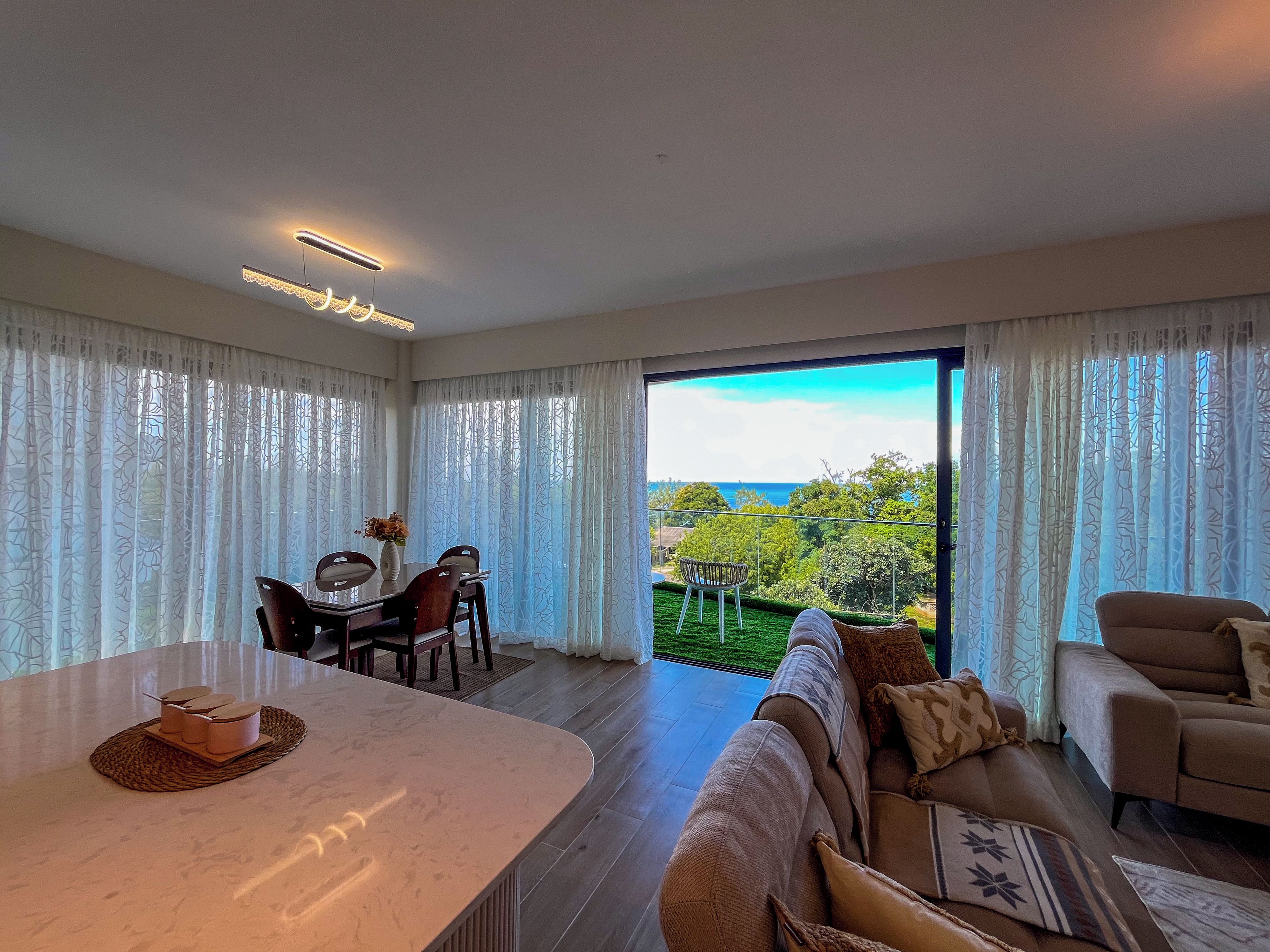 Amplia sala de estar con mesa de comedor, sofá y vistas al exterior.