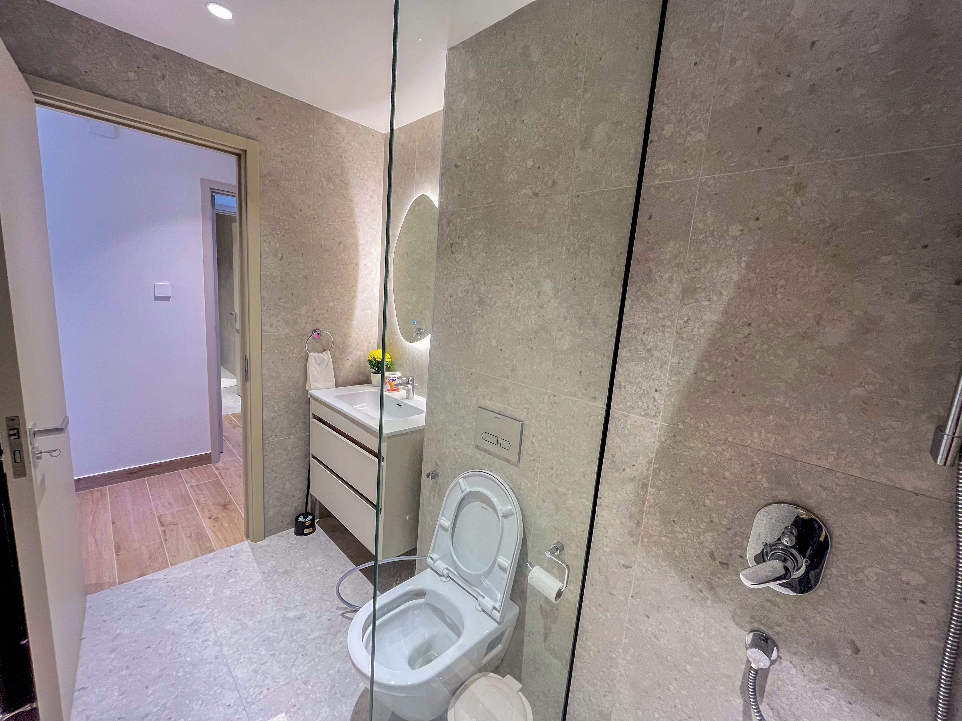 Un baño moderno con ducha envuelta en vidrio, inodoro y lavabo con espejo superior.