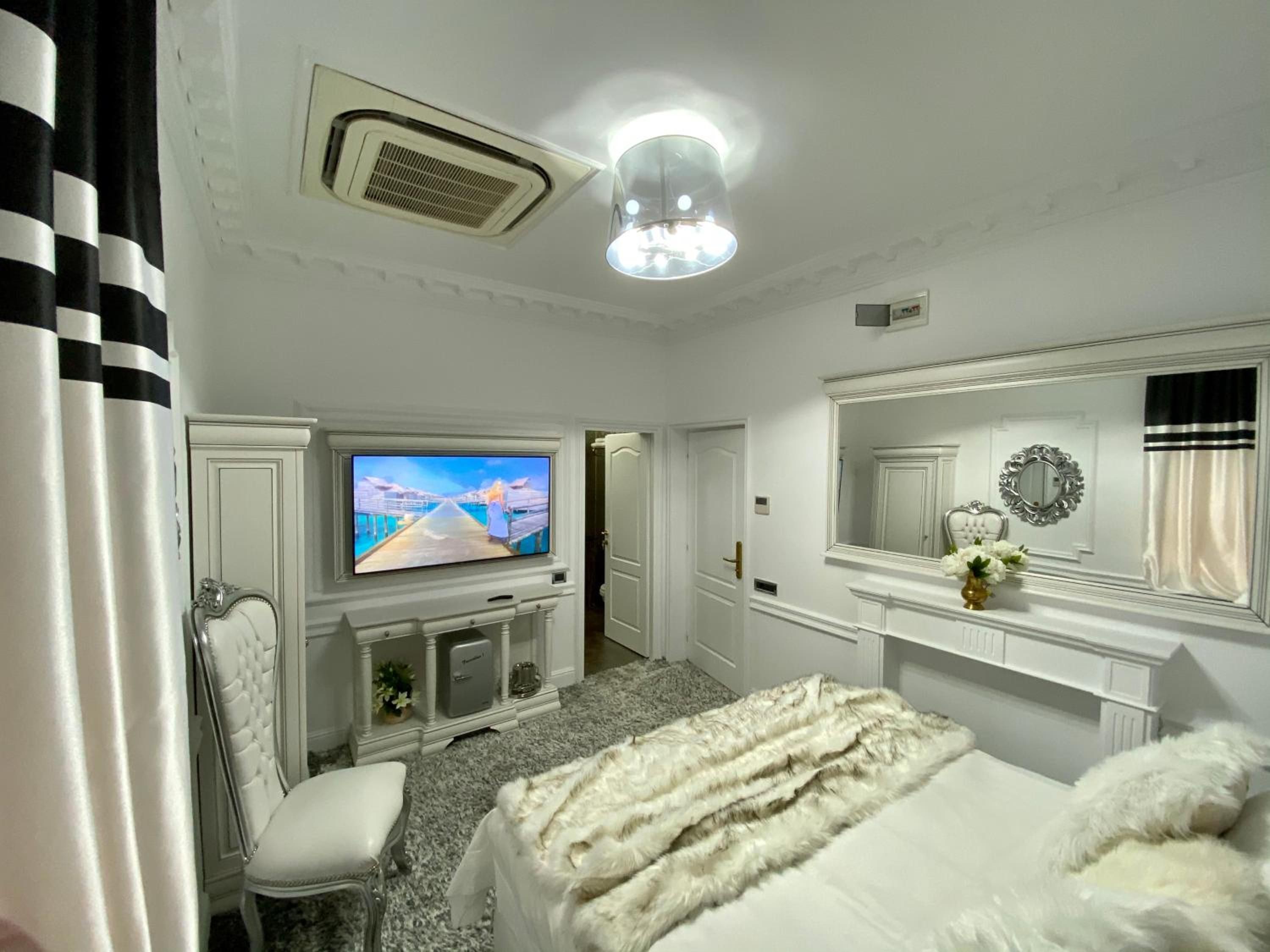 Habitación de hotel con televisión, cama, silla, espejo y chimenea.