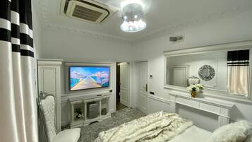 Habitación de hotel con televisión, cama, silla, espejo y chimenea.