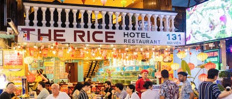 A bustling restaurant with a sign reading 'The Rice Hotel Restaurant 131.'