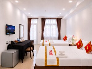 A hotel room with two beds, a desk with a computer, a refrigerator, and a television mounted on the wall. - The Rice Hotel 121 Bui Vien (Ho Chi Minh City)
