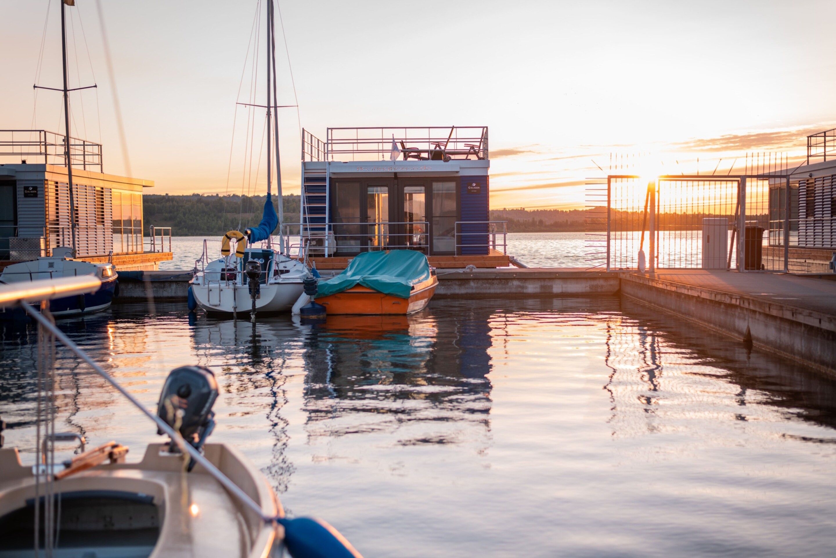 A marina with boats docked, a lifebuoy, and a small building labeled 'Floatinghouse'.