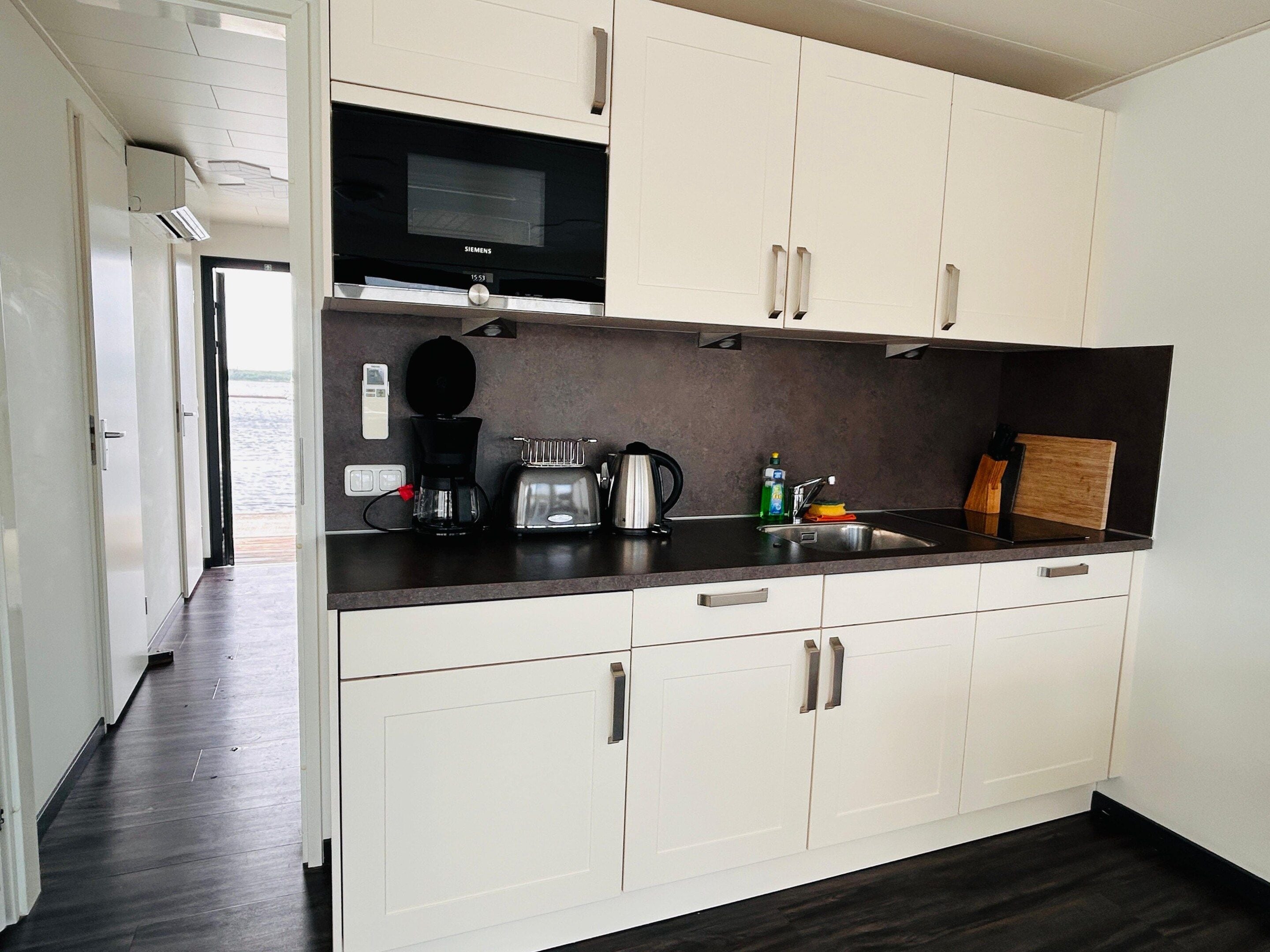 A modern kitchen with white cabinets, a black microwave, a coffee maker, and a toaster.