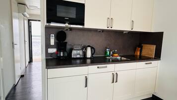 A modern kitchen with white cabinets, a black microwave, a coffee maker, and a toaster.