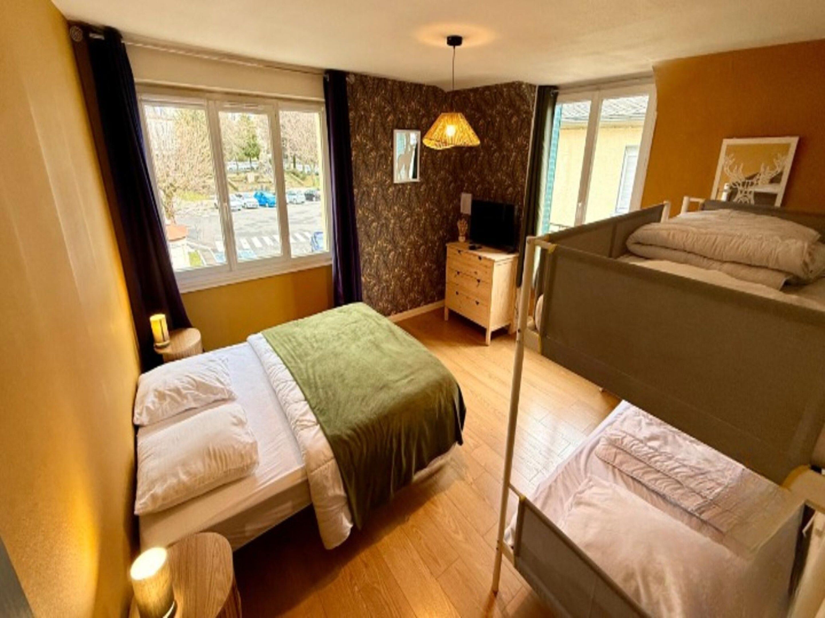 A hotel room with two beds, a dresser, a television, and a window with a view of the outside.