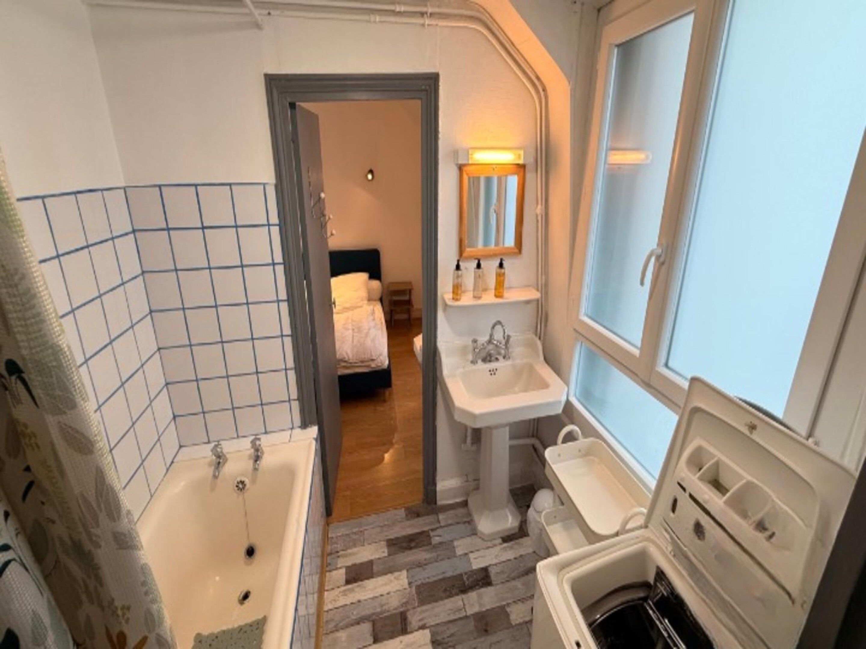 A bathroom with a bathtub, a sink, and a window.