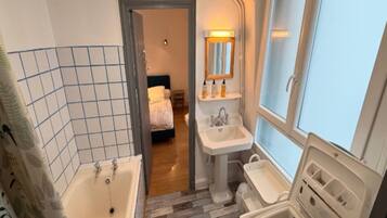 A bathroom with a bathtub, a sink, and a window.