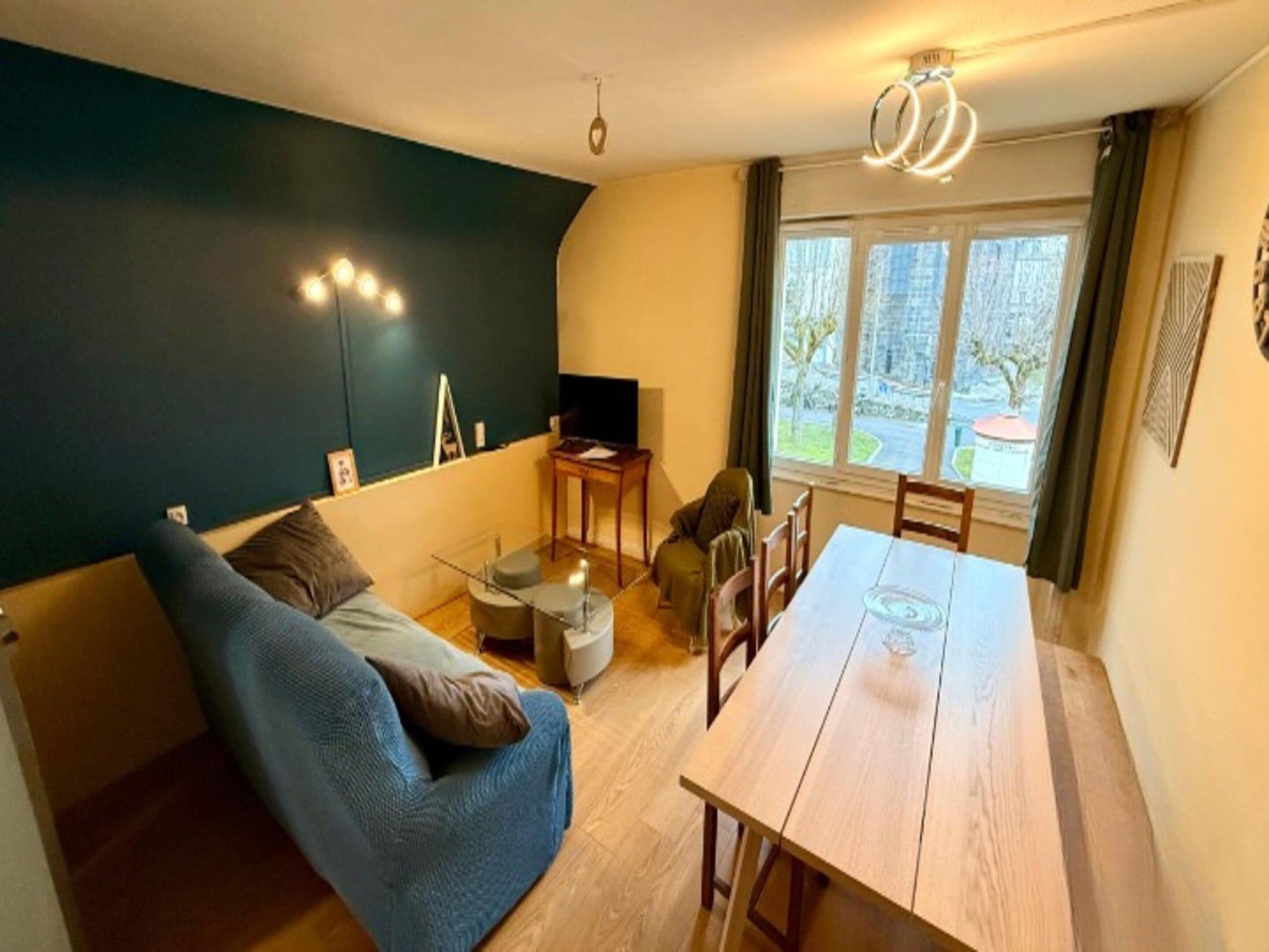 Un salon avec un canapé, une table et une fenêtre donnant sur l’extérieur.