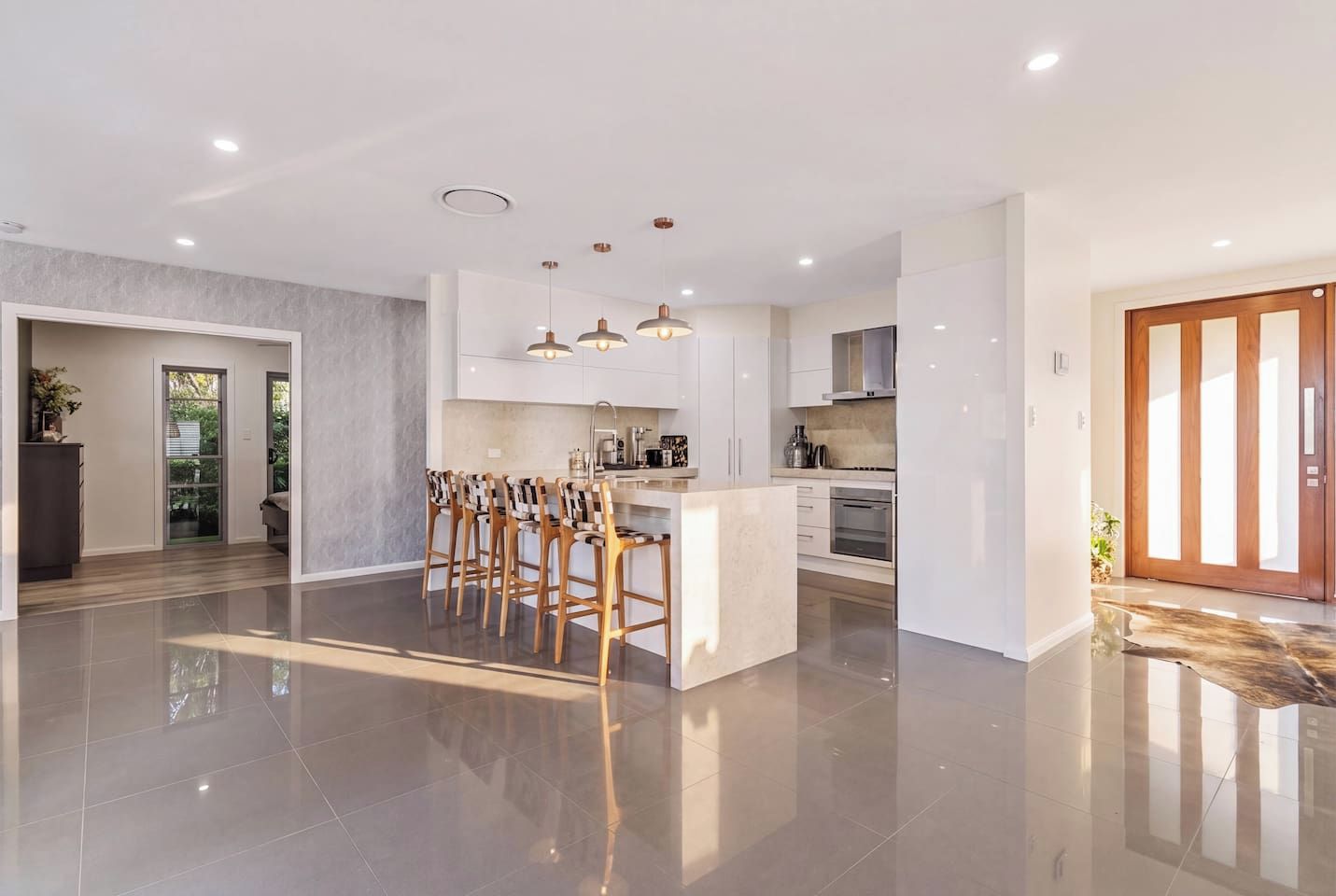 Een moderne keuken met een centraal eiland, hanglampen en uitzicht op buiten.
