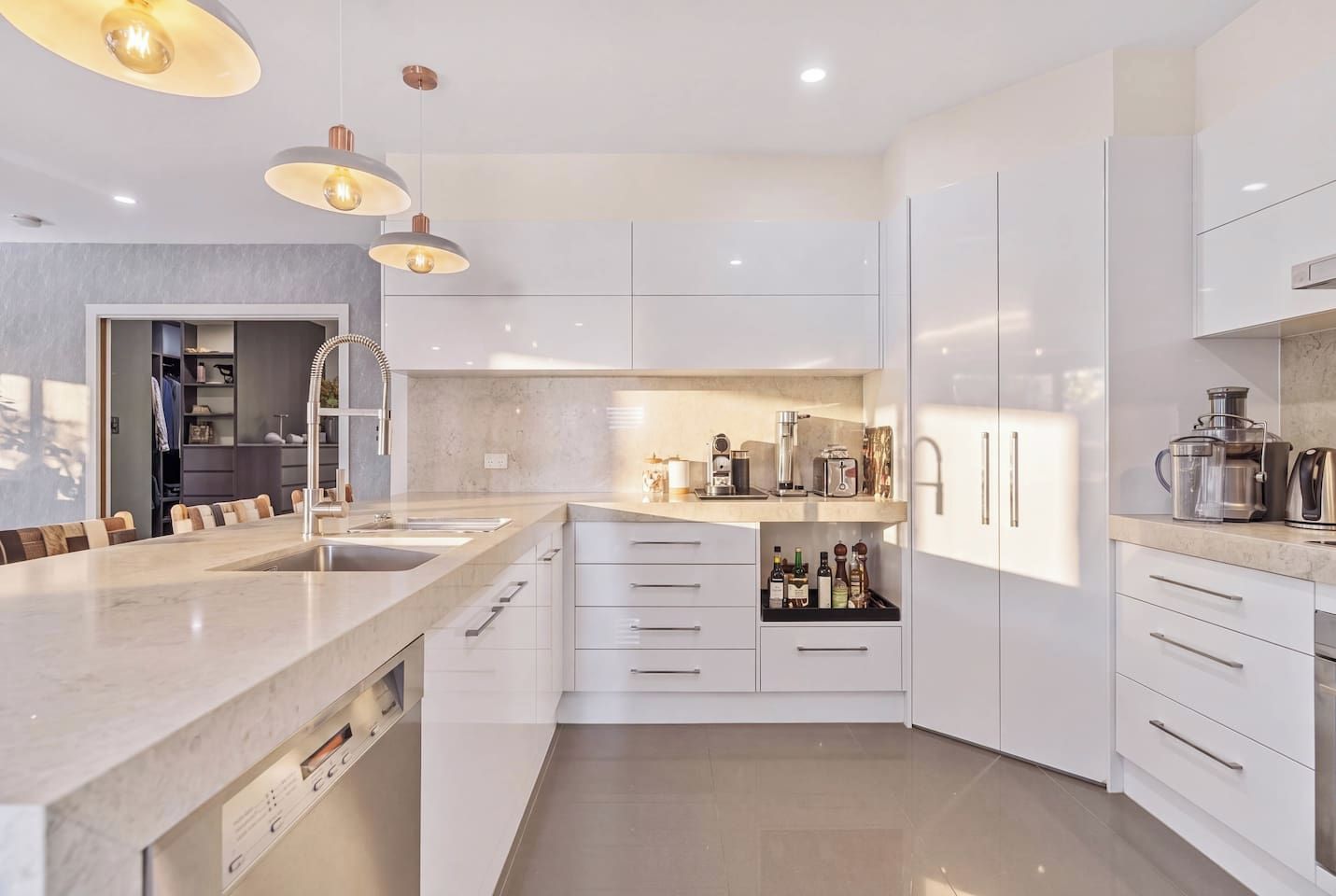 Una cocina moderna con una isla grande, armarios blancos e iluminación colgante.