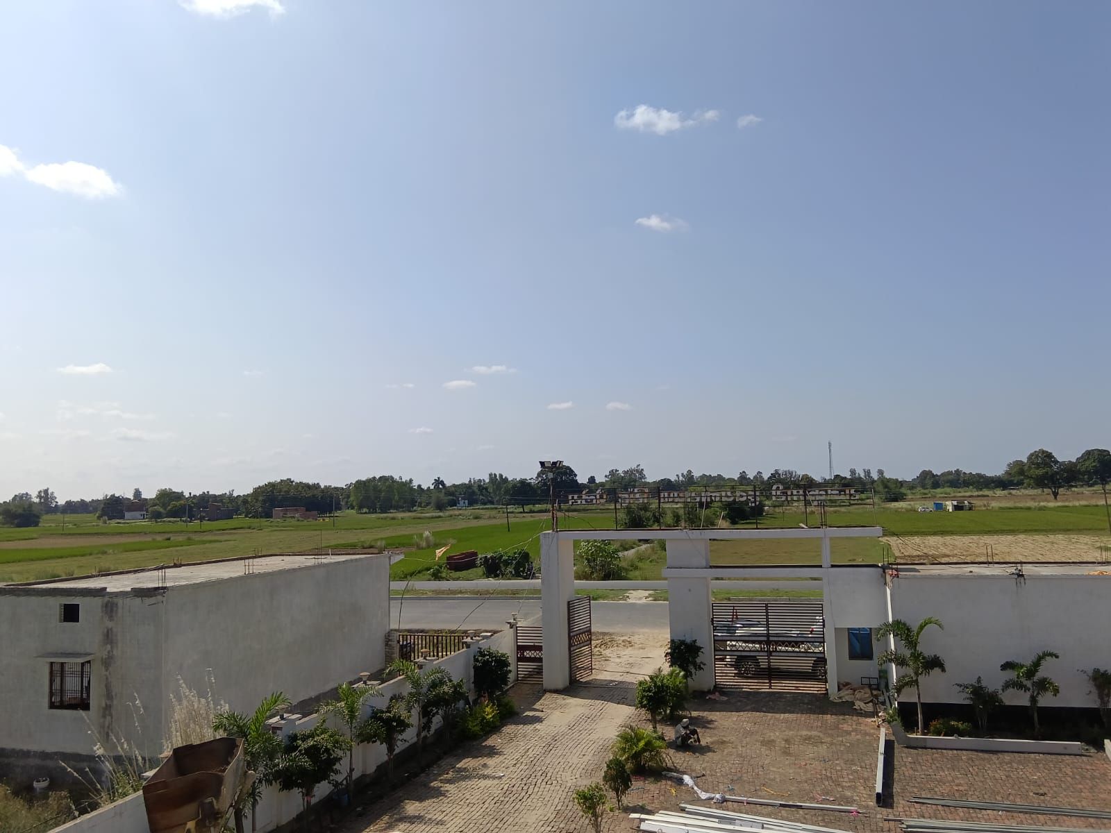 A gated entrance to a residential area with a paved pathway leading to a white building.