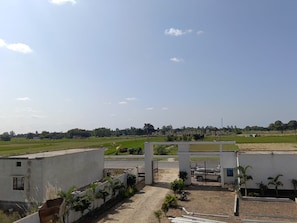 A gated entrance to a residential area with a paved pathway leading to a white building. - Wishotel Resort Rajkumari Hridya Palace  (Padri Gajarat)