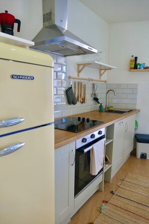 A compact kitchen with a built-in oven, a stove, and a refrigerator. - Cosy Asturian home 10 minutes from Rodiles & Villaviciosa - pet friendly! (Villaviciosa)