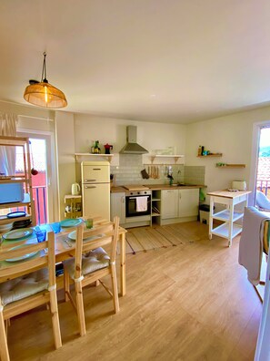 Eine moderne Küche mit Essbereich, Holzmöbeln und einer hängenden Leuchte.