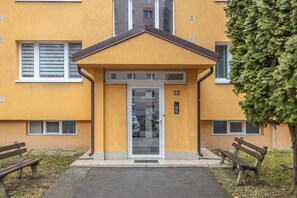 A yellow building with a brown roof, a glass door, and the number 32 on the wall.