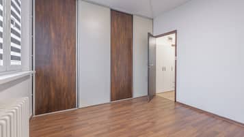 Habitación con piso de madera, armario de puertas correderas y radiador.