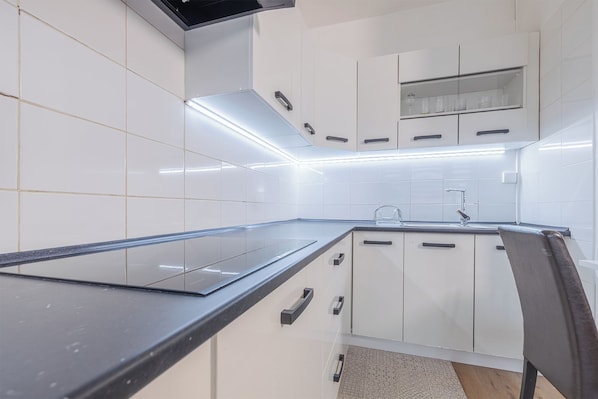 A modern kitchen with white cabinets, a black countertop, and a built-in oven.