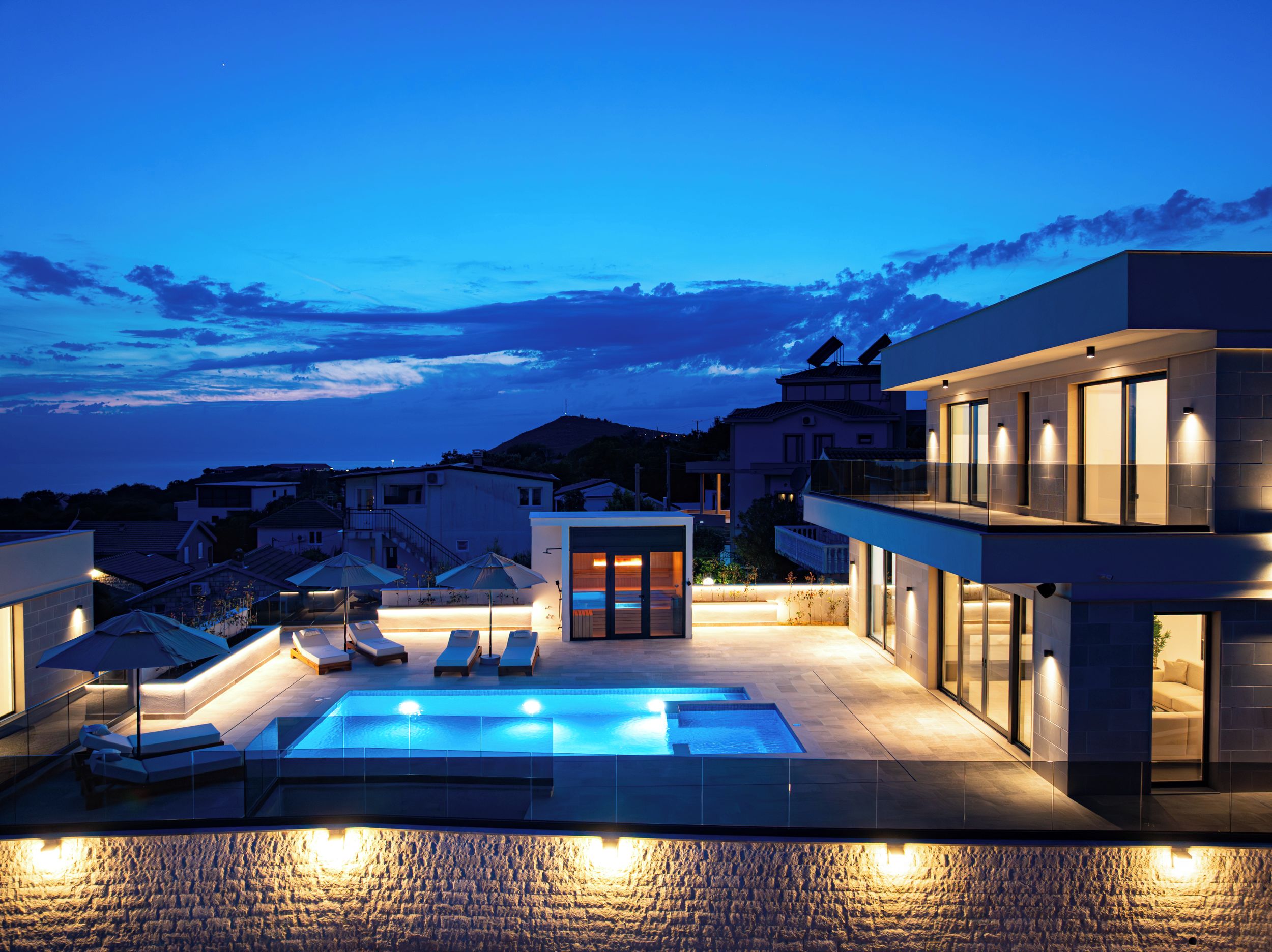 A rooftop pool area with lounge chairs and a small seating area, surrounded by modern buildings.