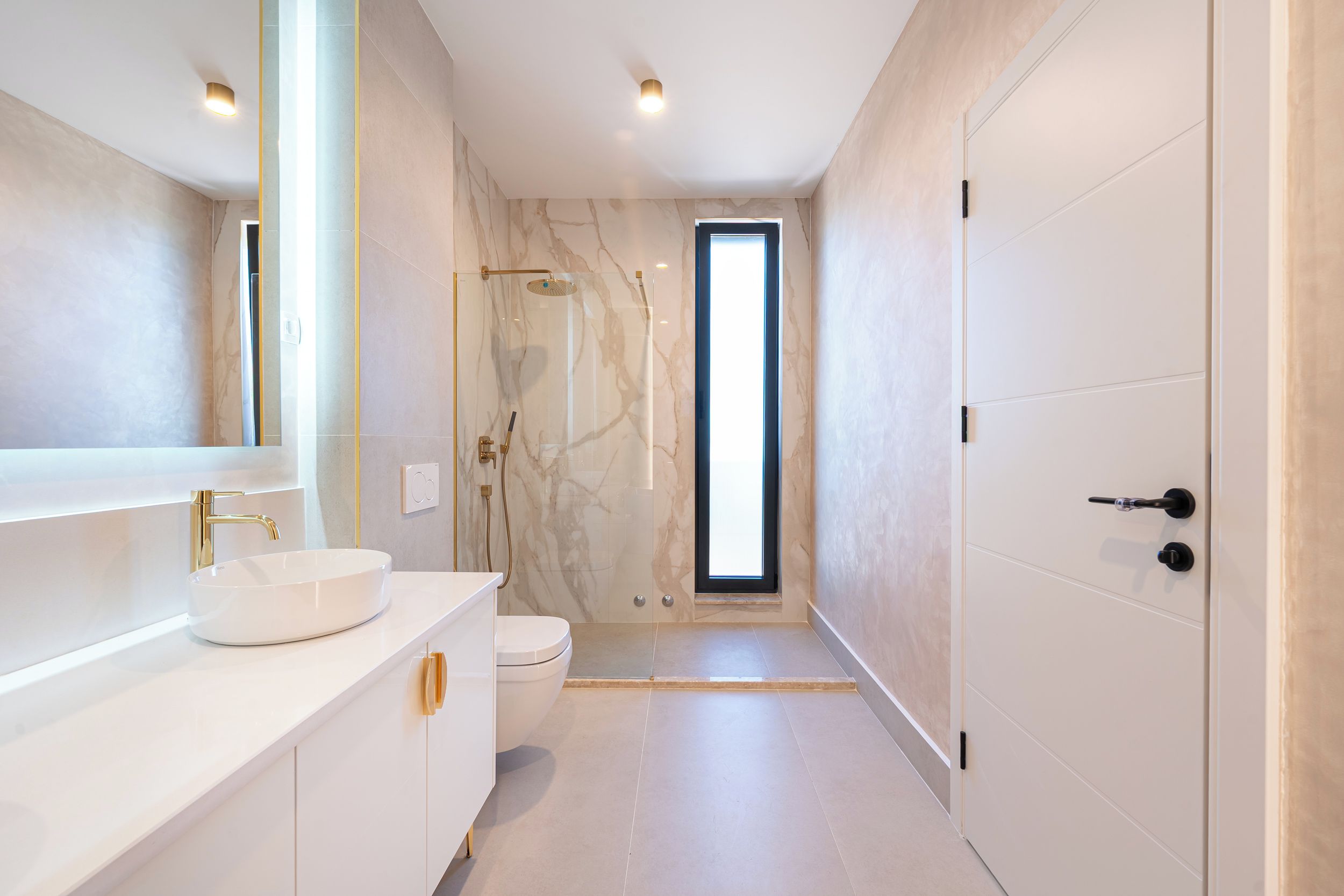 A modern bathroom with a white vanity, a large mirror, a shower with a glass door, and a toilet.
