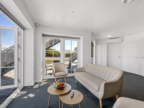 A modern living room with a sofa, a small round table with a fruit bowl, and a chair. - "Alban" - 50m to the fjord by Interhome (Tarm)