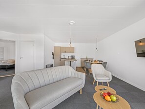 A modern living room with a sofa, a dining table with chairs, and a kitchen area in the background. - "Alban" - 50m to the fjord by Interhome (Tarm)