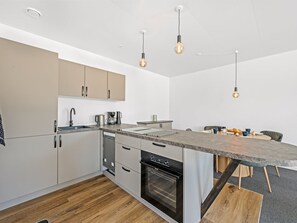 A modern kitchen with a central island, built-in oven, and pendant lighting. - "Alban" - 50m to the fjord by Interhome (Tarm)