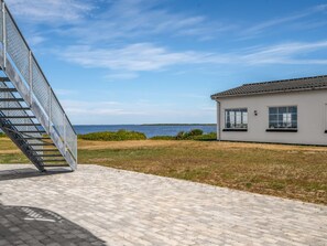 A coastal property with a paved walkway, a metal staircase, and a white building with large windows. - "Alban" - 50m to the fjord by Interhome (Tarm)