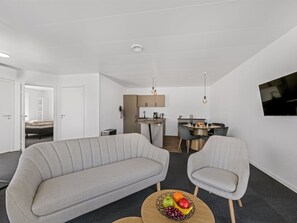 Een moderne woonkamer met een bank, fauteuil en salontafel met fruit.