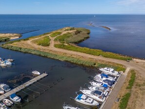 Un port de plaisance avec des bateaux amarrés, un chemin de terre et une étendue d’eau.