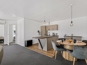 A modern kitchen with a central island, wooden flooring, and a dining area with a round table and chairs. - "Apsolon" - 50m to the fjord by Interhome (Tarm)