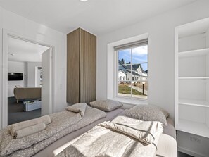 Une chambre moderne dotée d’une grande fenêtre, d’une armoire intégrée et d’un téléviseur à écran plat.
