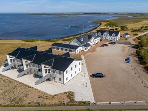 Une propriété située sur la côte, comprenant plusieurs bâtiments, un espace de stationnement et une plage.