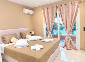 A hotel room with a bed, pillows, a nightstand, an air conditioner, and a view of the outdoors. - La Casa Di Kosta dream house in Kontogialos (Kontogialos)