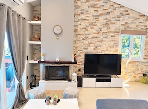Una sala de estar moderna con chimenea, televisor de pantalla plana y pared con diseño de piedra.