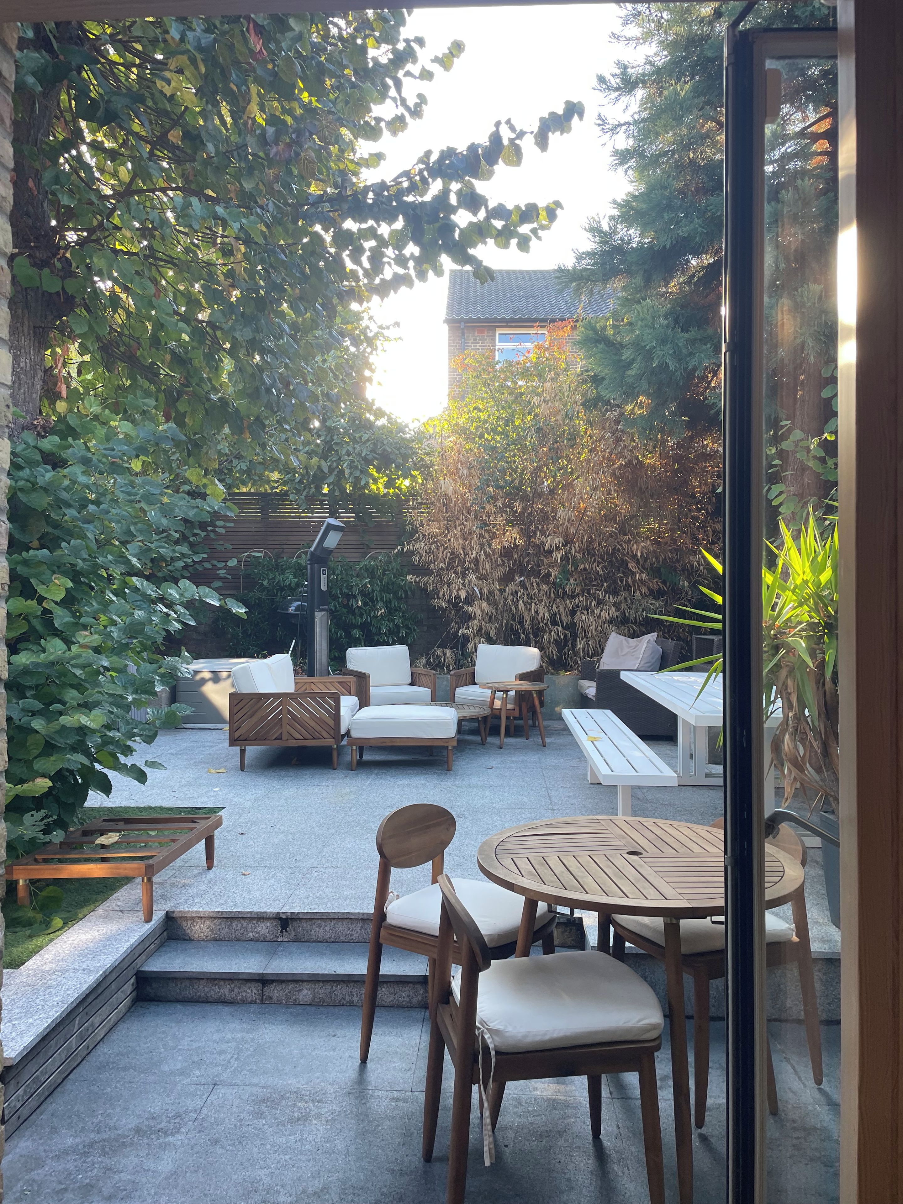 Un espace patio aménagé avec du mobilier d’extérieur, un foyer et une vue sur un bâtiment en arrière-plan.