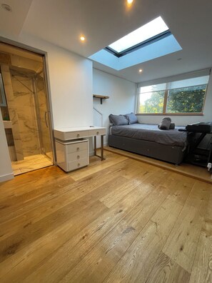A modern bedroom with a skylight, a bed, a desk, and a walk-in closet. - Modern four story house In Canonbury / Islington (London)