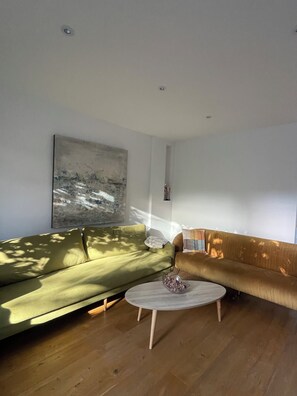 A modern living room with two sofas, a coffee table, and a large abstract painting on the wall. - Modern four story house In Canonbury / Islington (London)