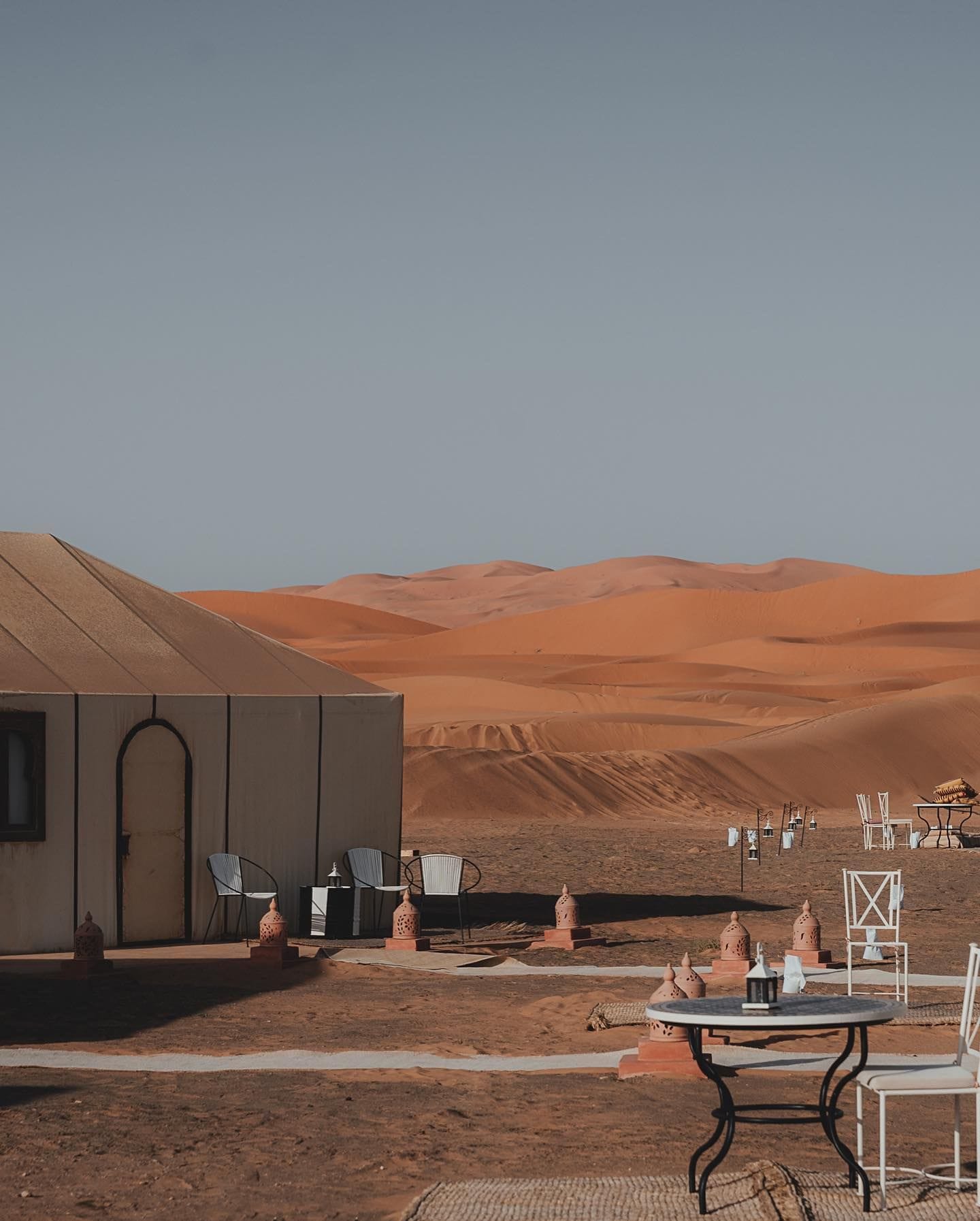 Paisaje desértico con un edificio y un área de estar al aire libre.