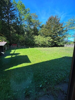 A grassy yard with a stone wall, trees, and a small building. - Authentic chalet for mountain lovers - near to Portes du Soleil skiing area (Val-d'Illiez)